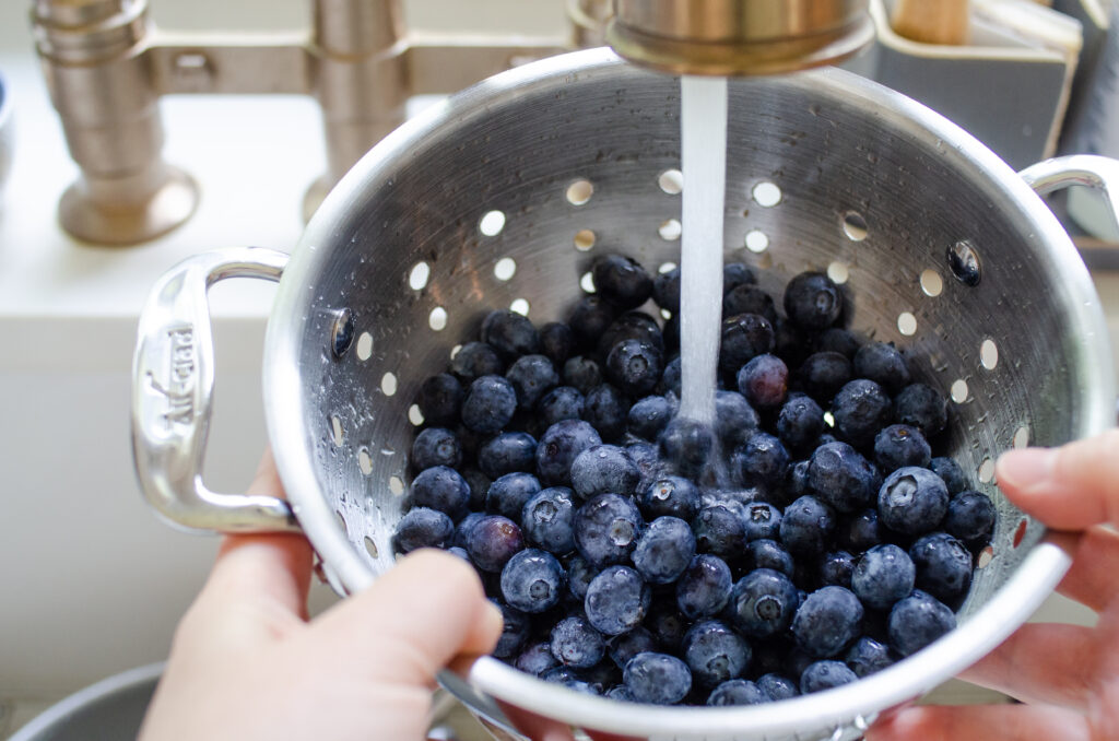 Washing blueberries in a colander.