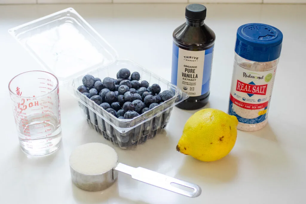 All of the ingredients needed to make a blueberry compote with fresh blueberries laid out on a white countertop.