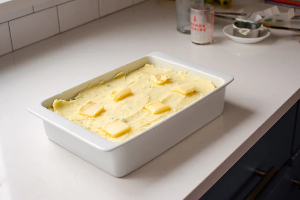 The mashed potatoes in the baking dish with pats of butter on top.