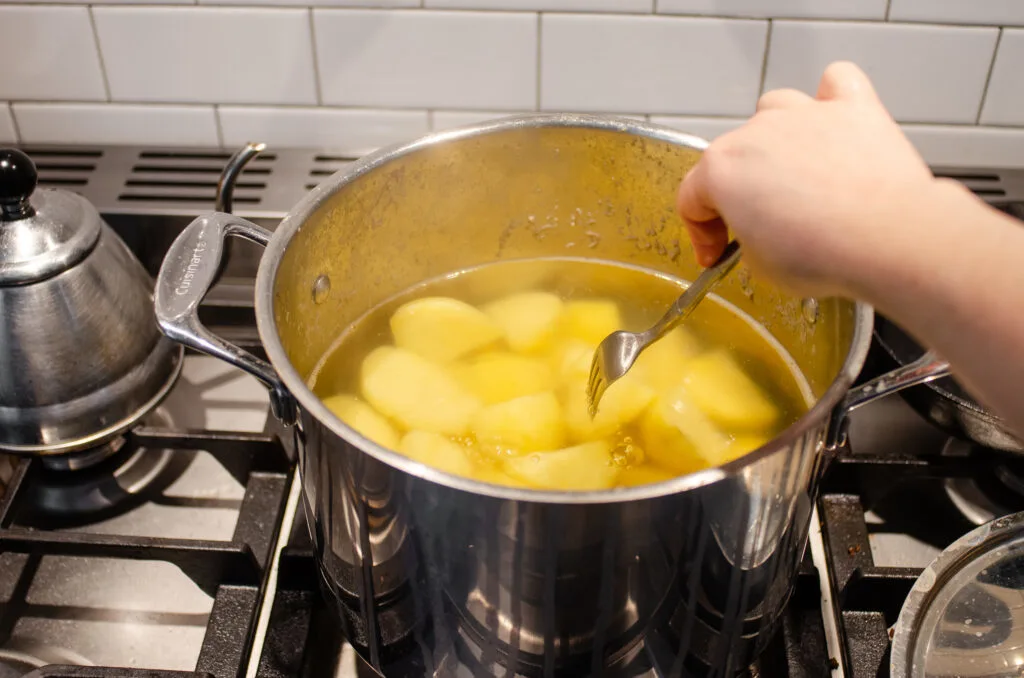 Testing the potatoes for doneness with a fork.