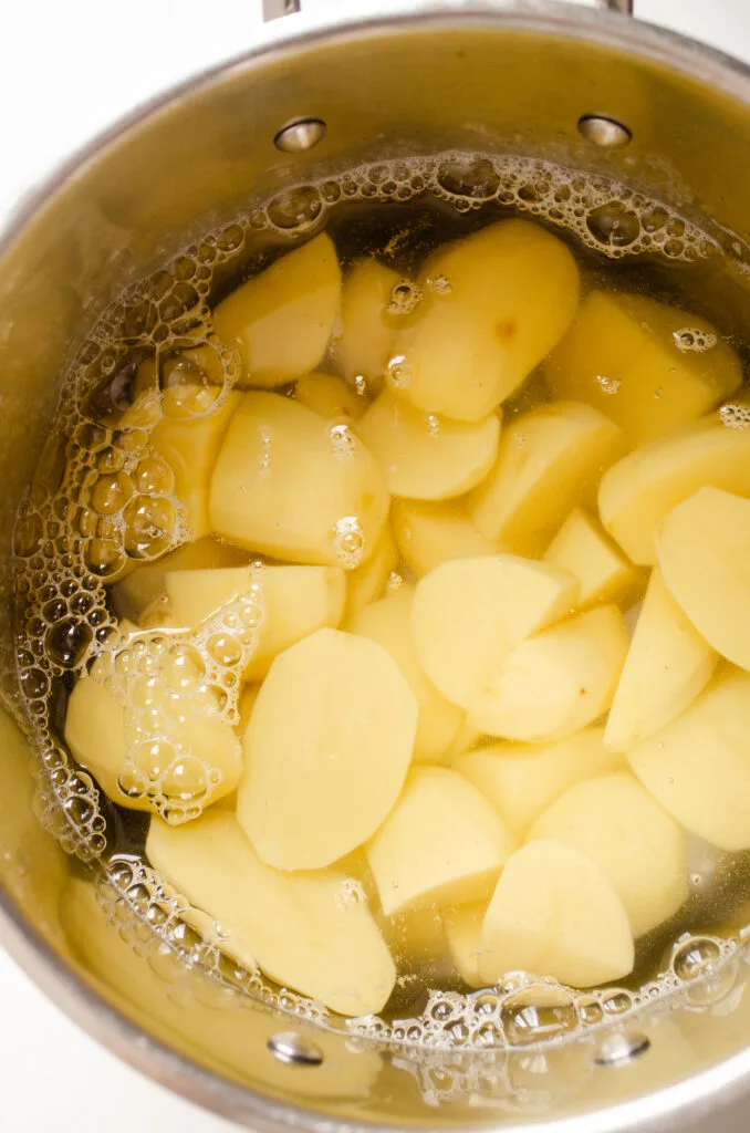 Quartered potatoes in a large pot covered with water.