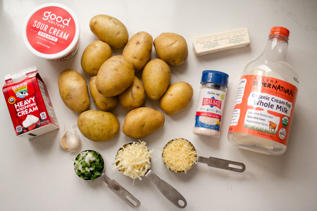 All of the ingredients needed to make the tasty version of baked mashed potatoes laid out on a white countertop. 