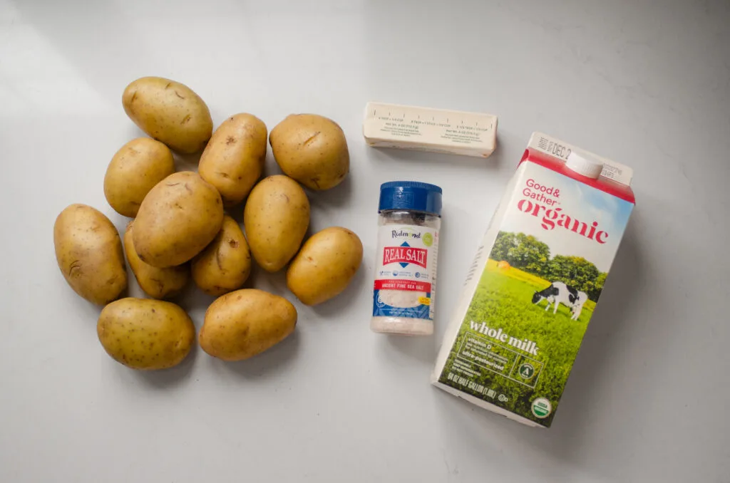All of the ingredients needed to make simple baked mashed potatoes laid out on a white countertop.