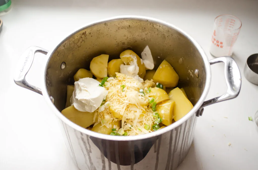 Adding all of the extra ingredients to the boiled potatoes.