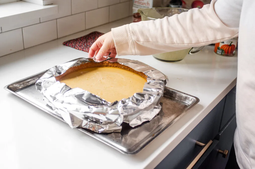 Placing aluminum foil around the edges of the pie to prevent the crust from burning.