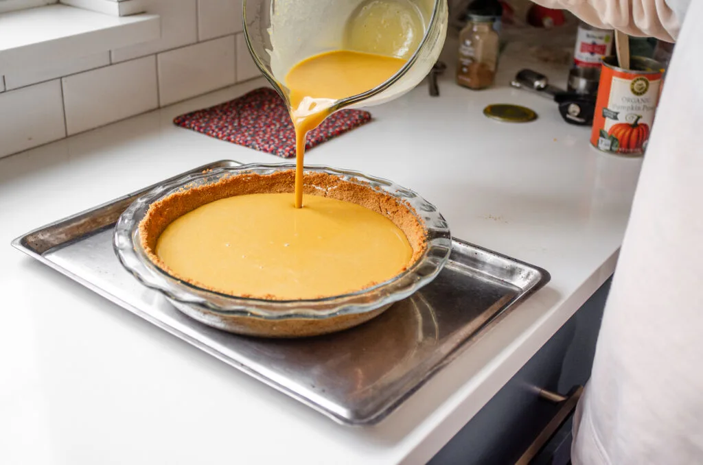 Pouring the pumpkin custard into the baked crust.