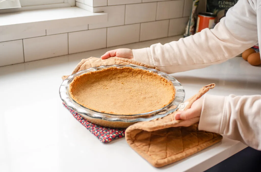 Placing the baked crust on a hot pad on the countertop to cool.