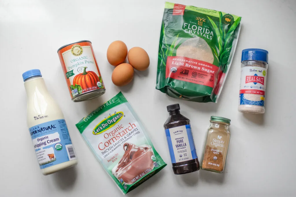 All of the ingredients needed for the custard portion of a pumpkin pie laid out on a white countertop.