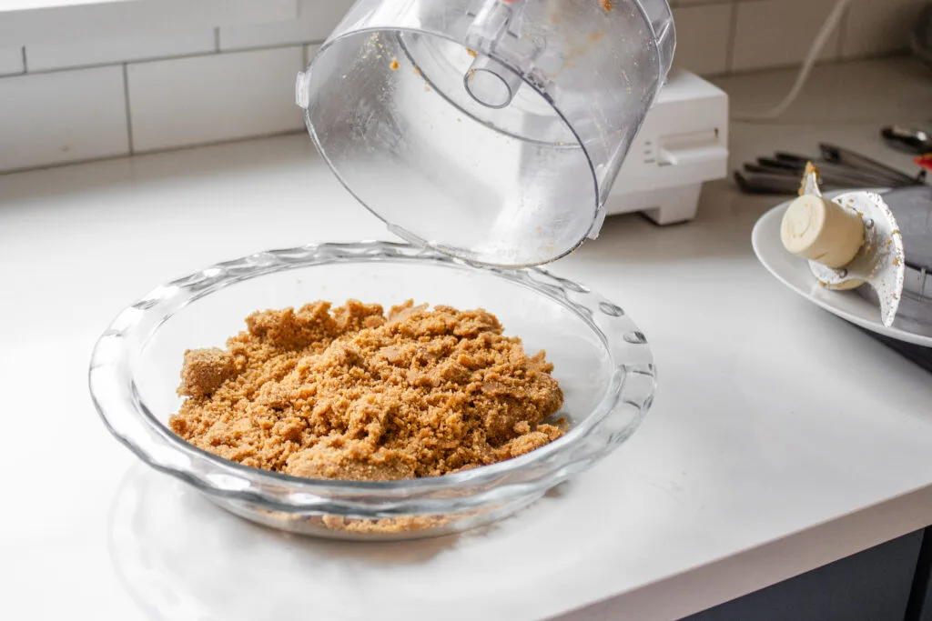 Pouring the graham cracker mixture into a pie pan.