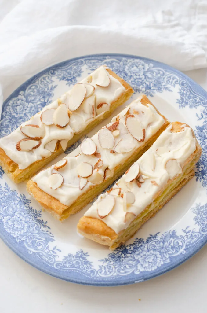 3 slices of Danish puff pastry dessert on a blue and white plate.