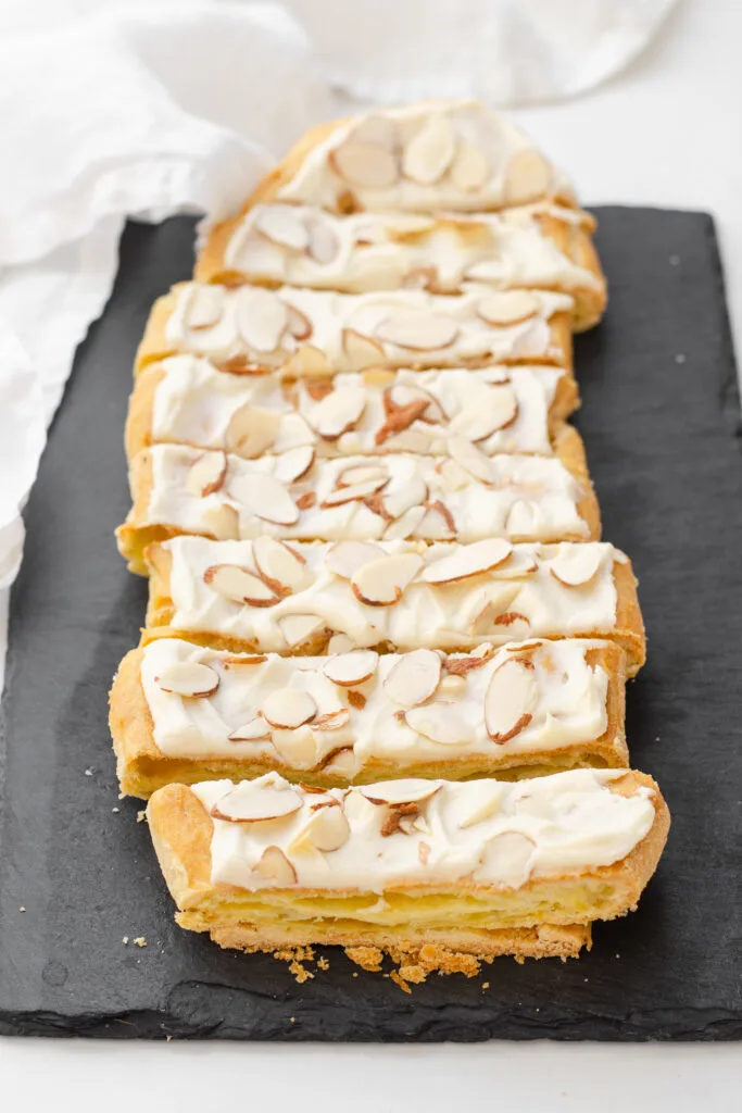 Slices of Danish puff pastry on a black slate board with a white napkin in the background.