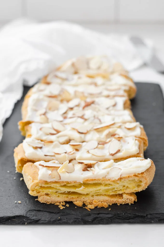 Slices of Danish puff pastry on a black slate board with a white napkin in the background.
