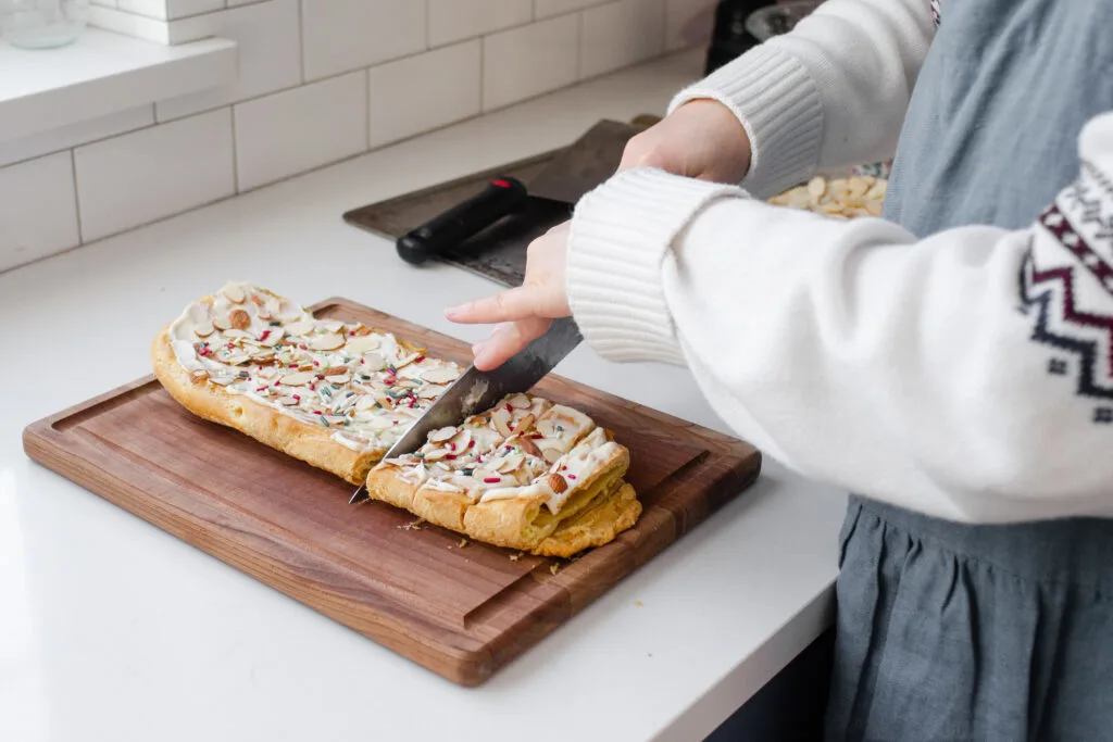 Cutting the Danish puff on a wooden cutting board.
