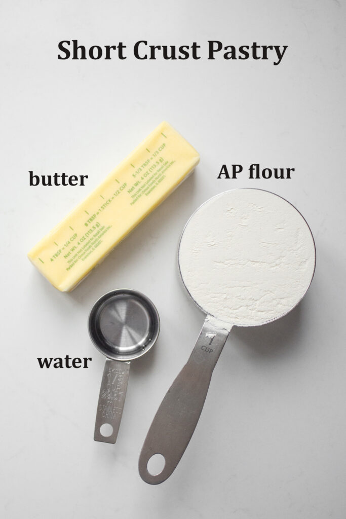All of the ingredients needed to make the short crust pastry laid out on a white countertop.