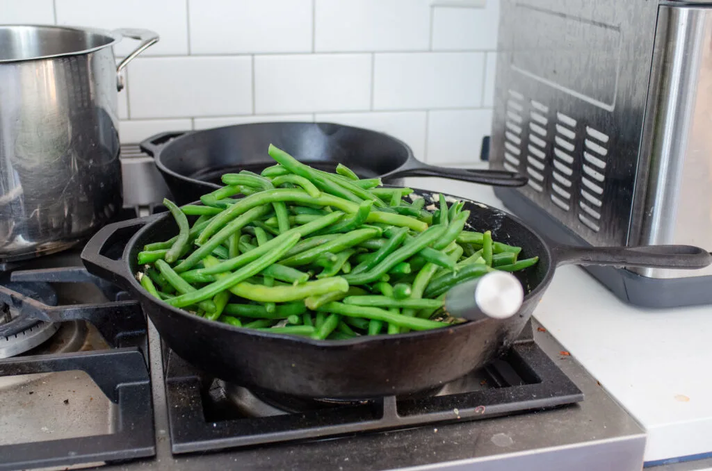 Adding the green beans to the skillet.