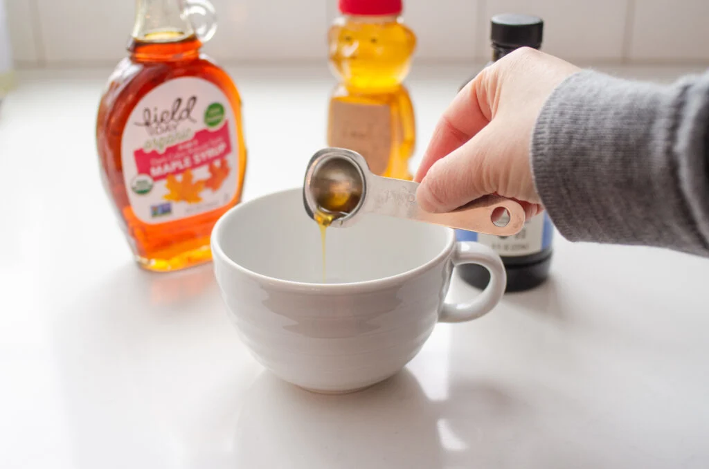 Pouring maple syrup into a latte cup.