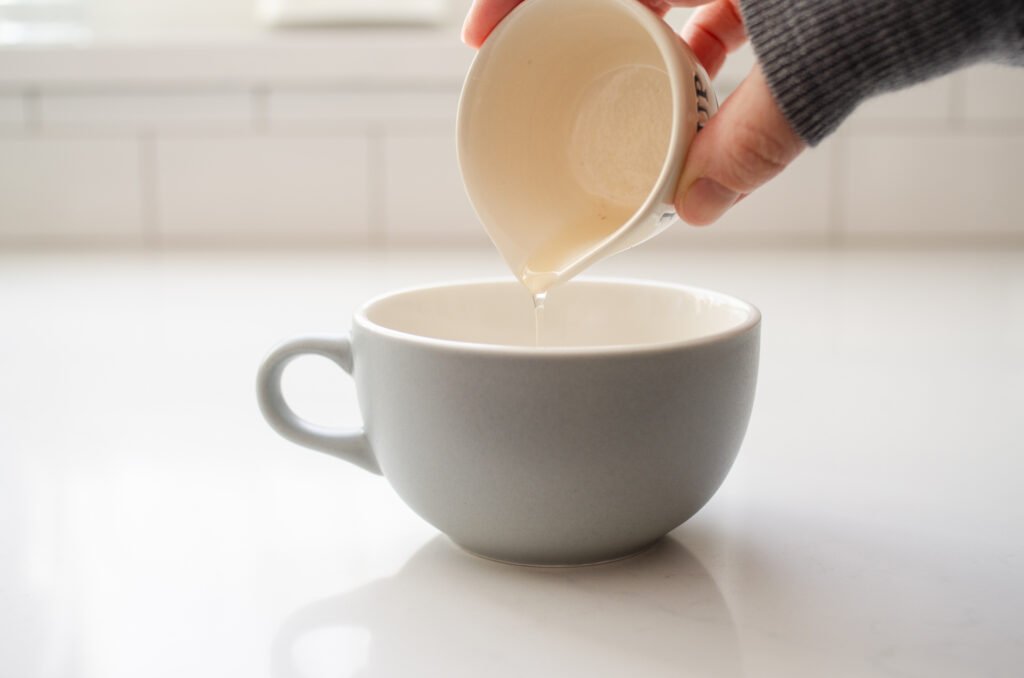 Pouring the single serving of vanilla syrup into a mug.