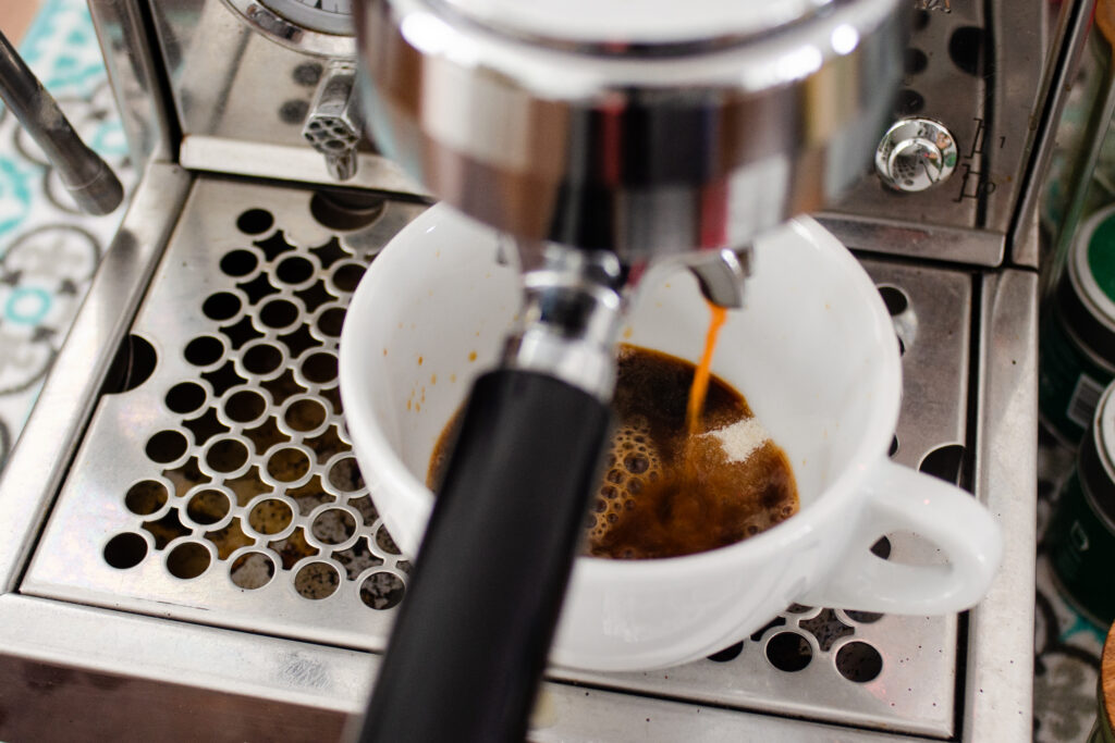 Pulling a shot of espresso on top of sugar and vanilla in a cup.
