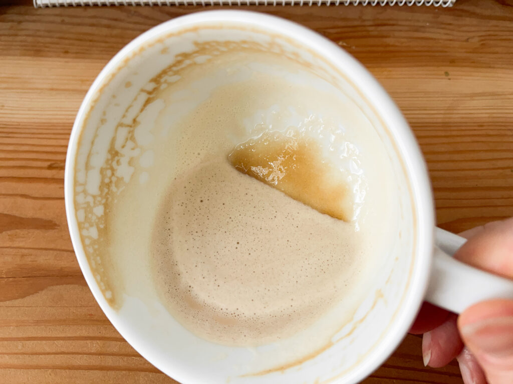 The dregs in a latte mug showing the unmixed granules of sugar.