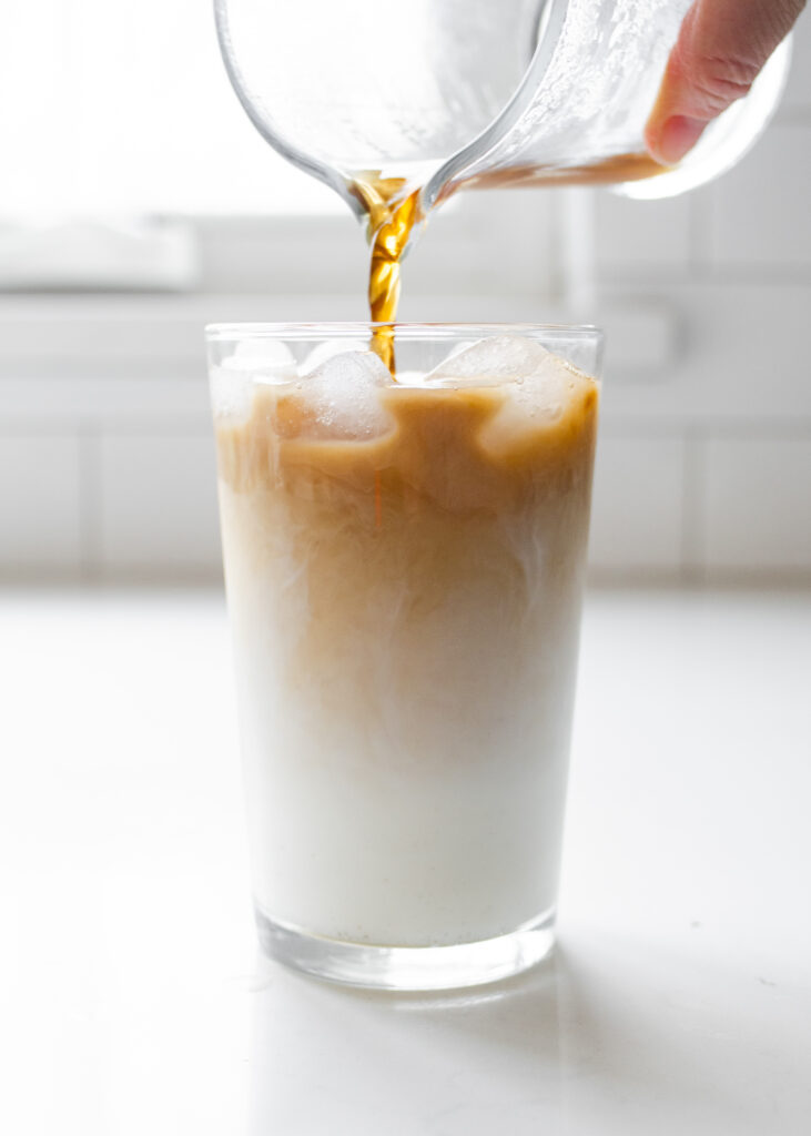 Pouring the brewed tea concentrate over the milk/cream/ice mixture in the glass.