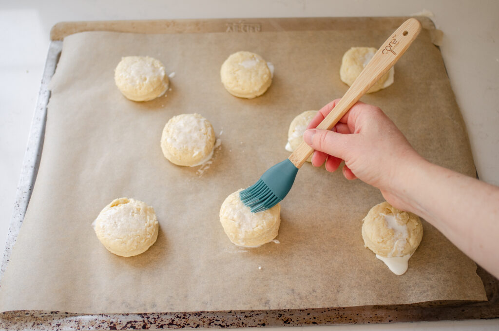 Brushing the cream out on top of the scones.