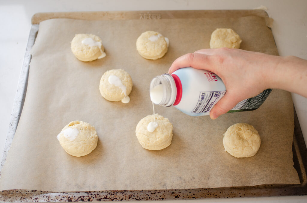 Pouring cream on top the sourdough scones before baking.