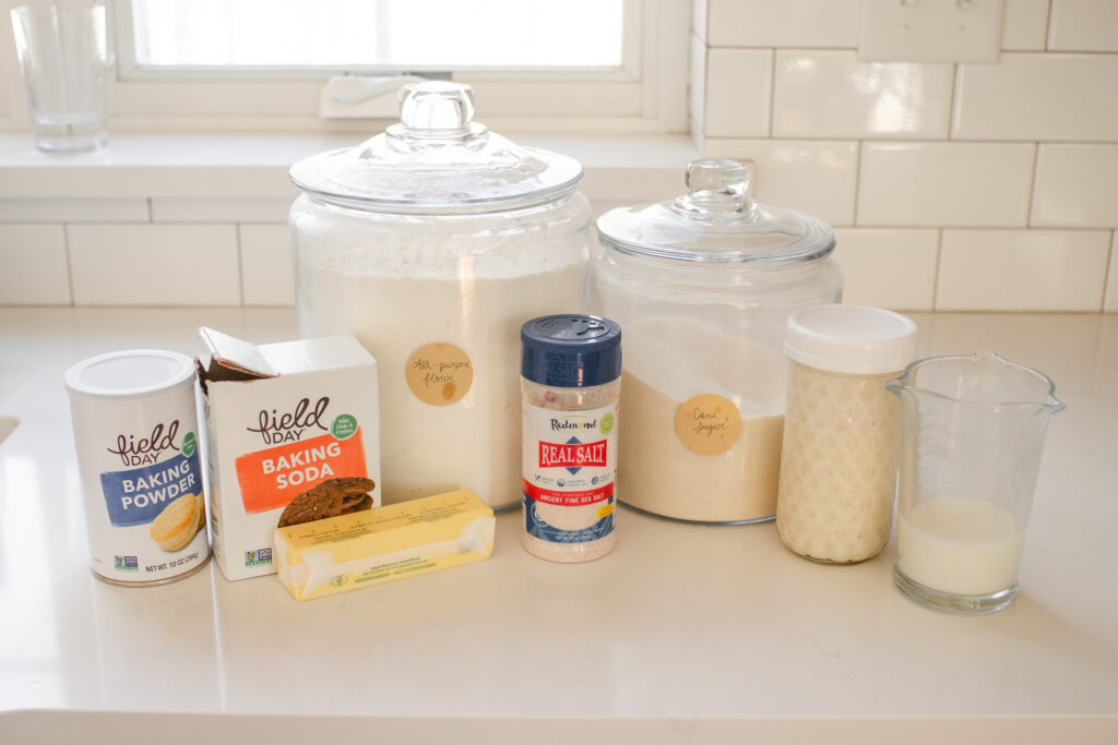 All of the ingredients needed to make sourdough scones laid out on a white countertop with a window in the background.