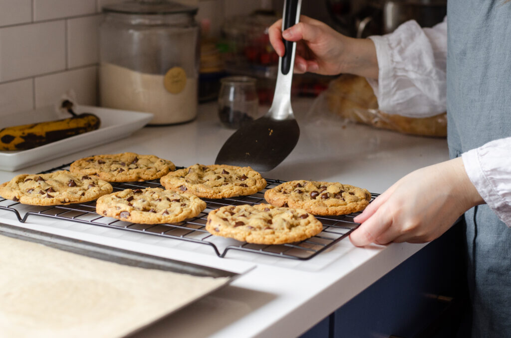 Transferring the cooled cookies onto a wire cooling rack.