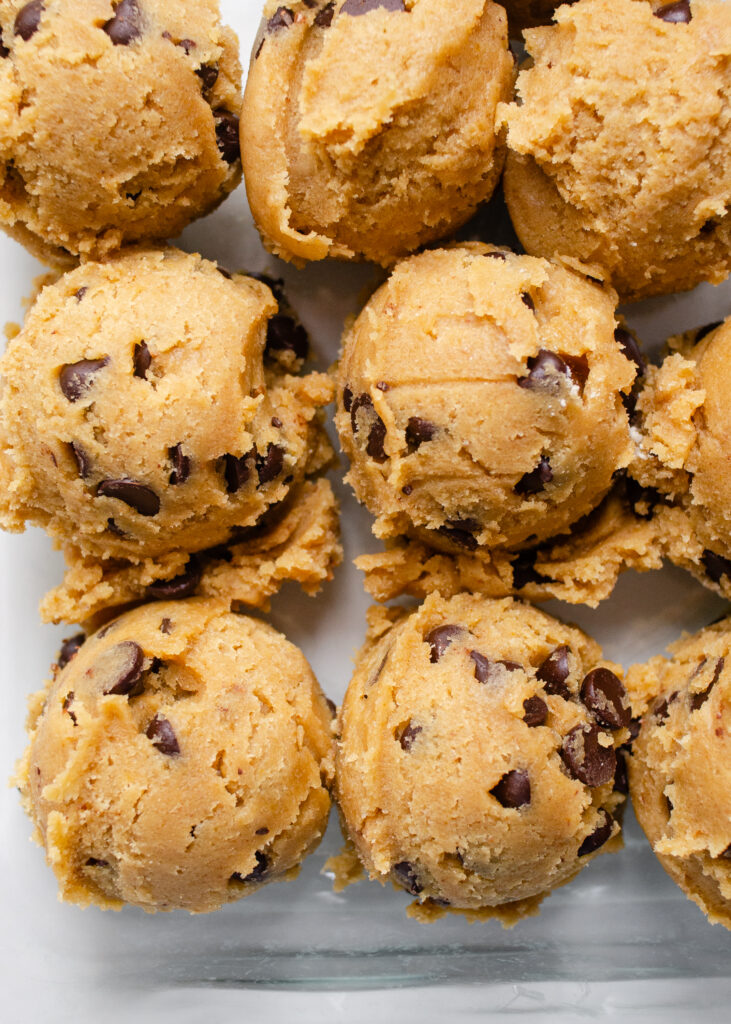 Scoops of einkorn flour cookie dough in a glass storage container. 