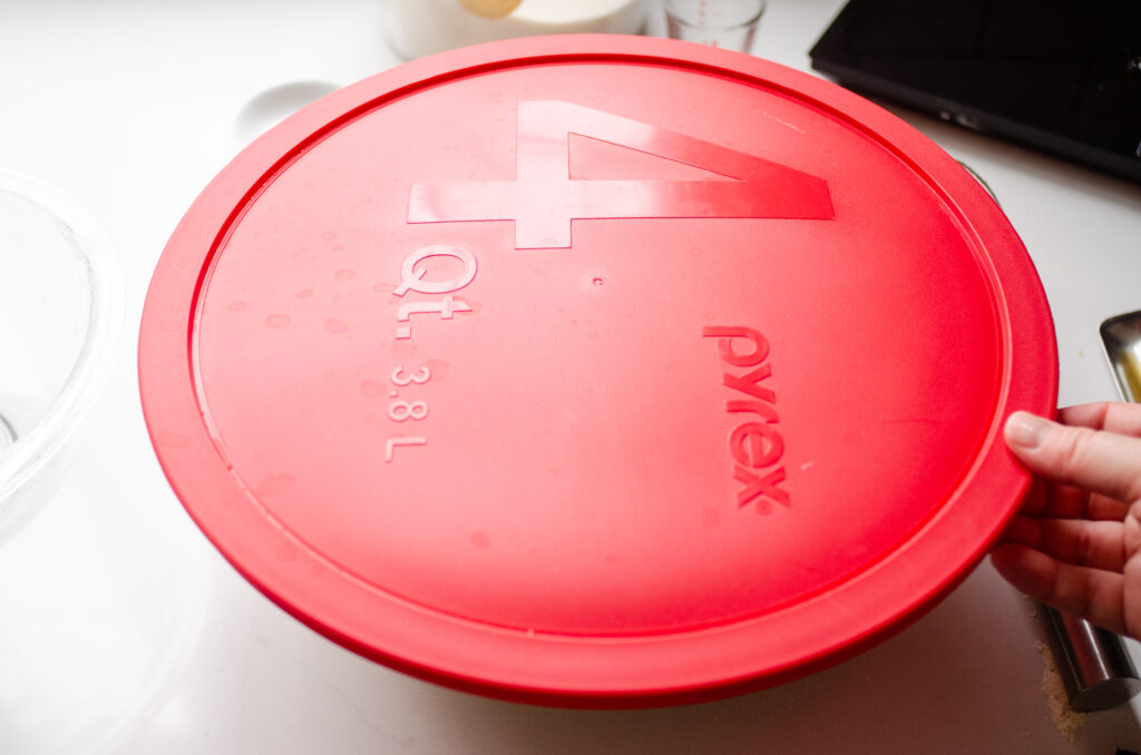 A large mixing bowl with a red lid on top.