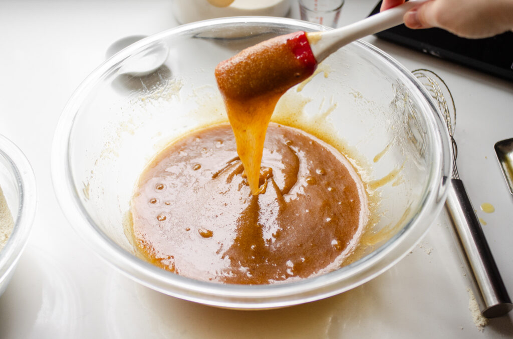 The butter/sugar mixture dripping off of a spatula back into the mixing bowl.