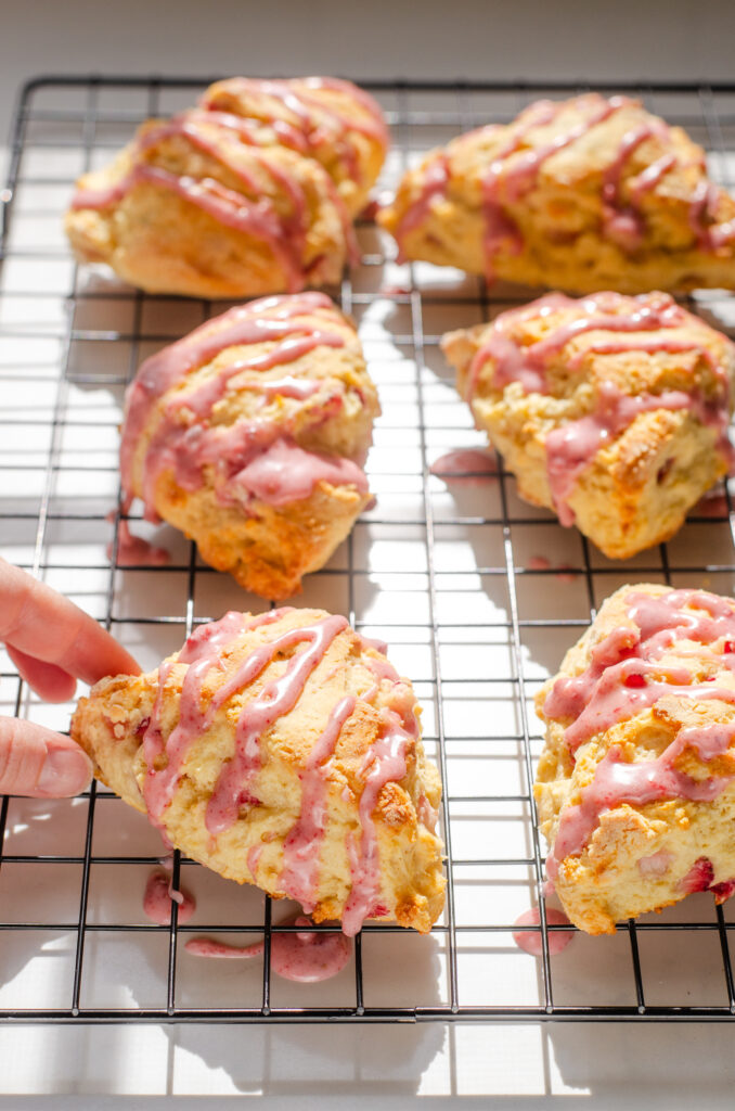 Strawberry scones on a wire cooling rack on a sunny counter.