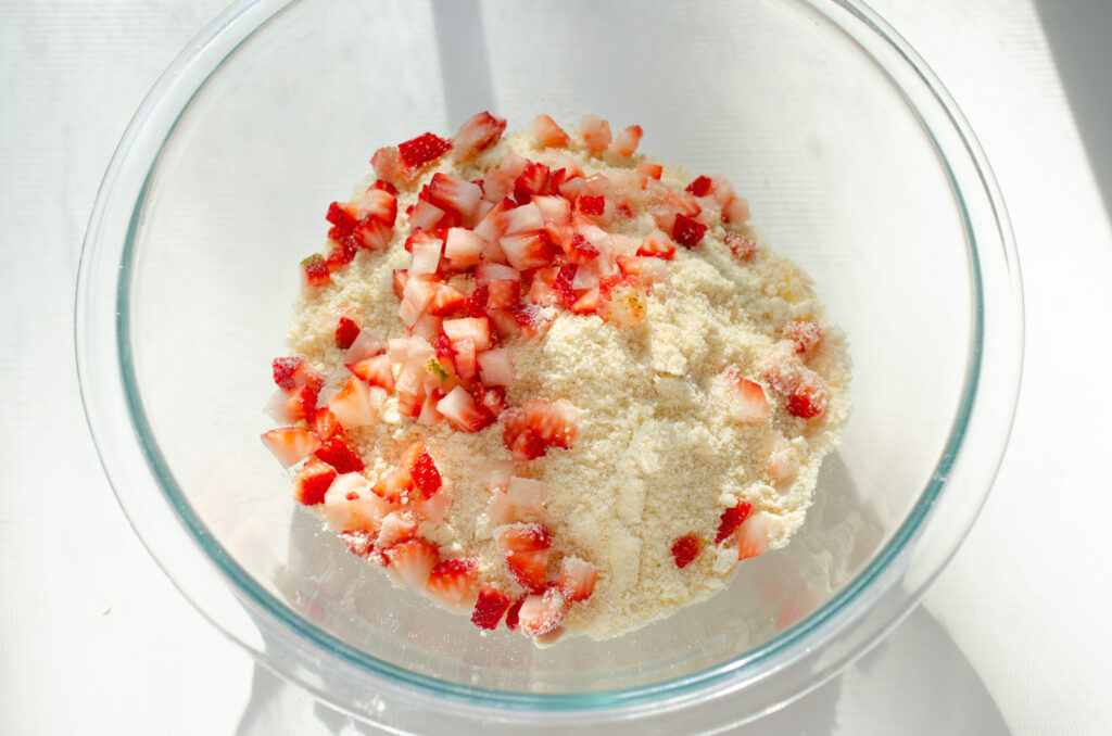 Fresh chopped strawberries in a bowl the dry ingredients needed to make scones.