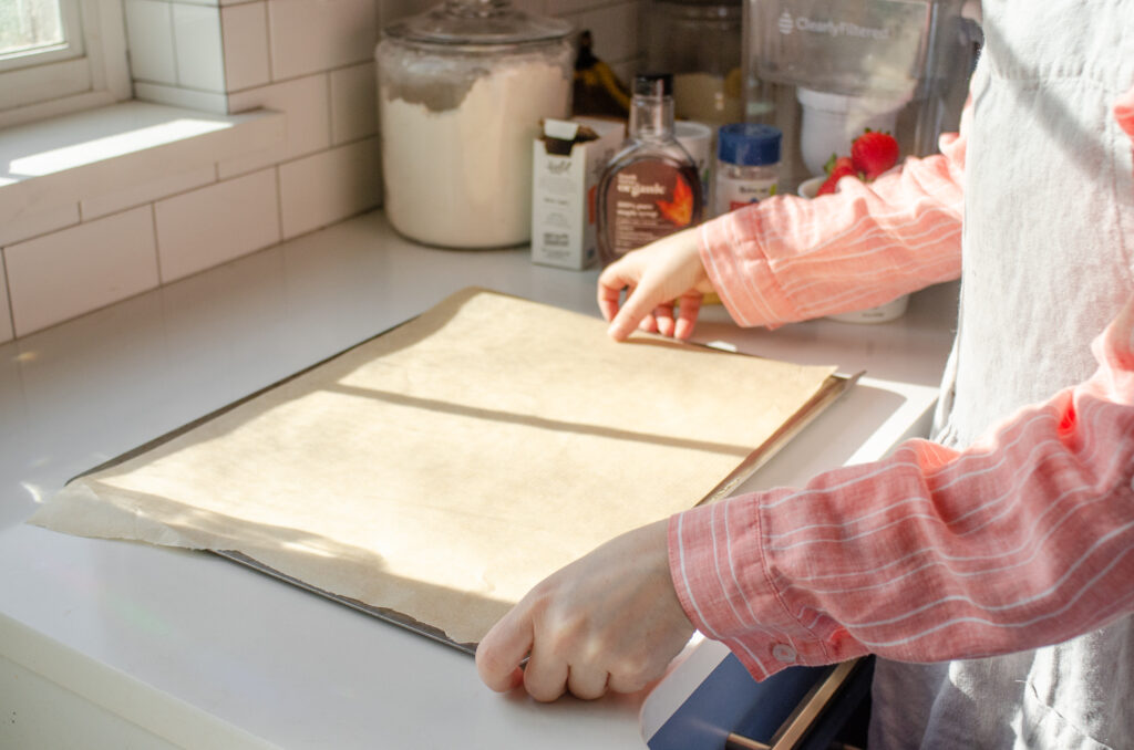 Lining a heavy duty baking sheet with parchment paper.
