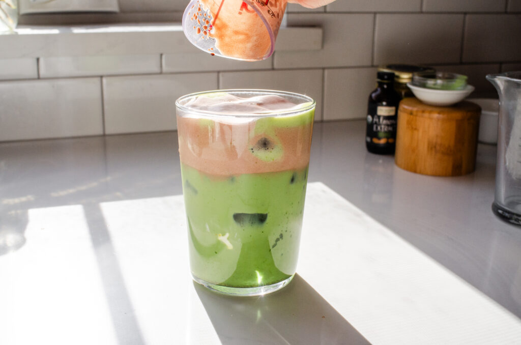Pouring the Chocolate Sweet Cream over the pistachio matcha latte.