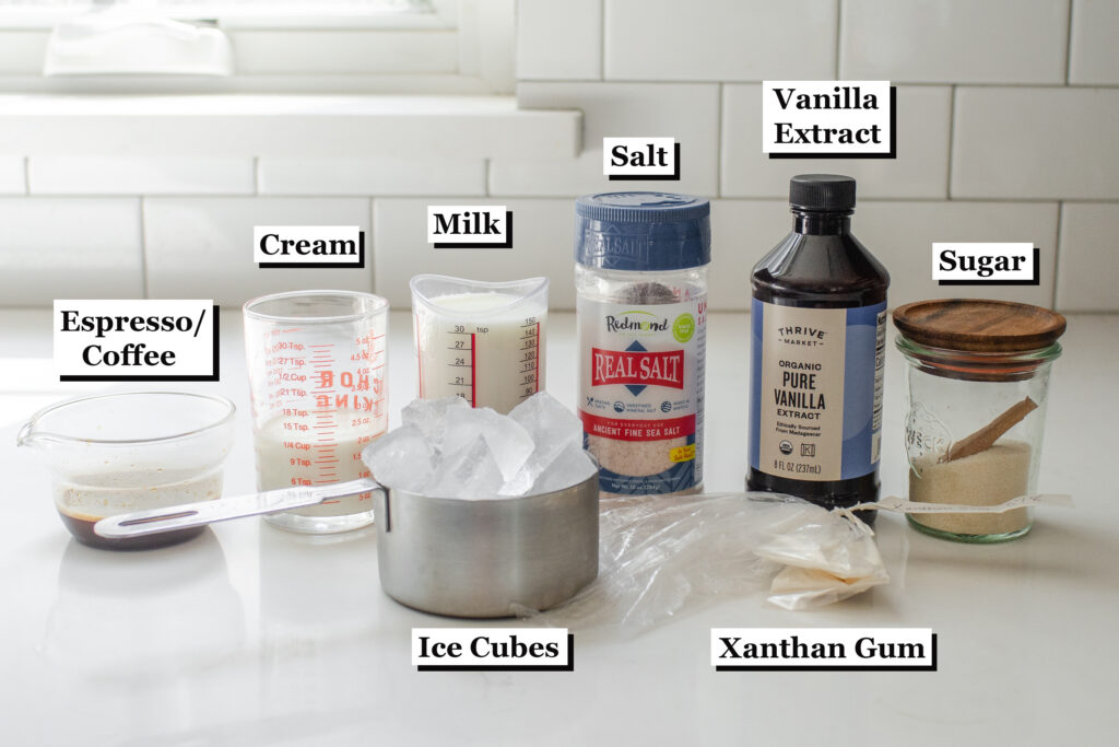 All of the ingredients needed to make a Starbucks Coffee Frappuccino laid out on a white countertop. 
