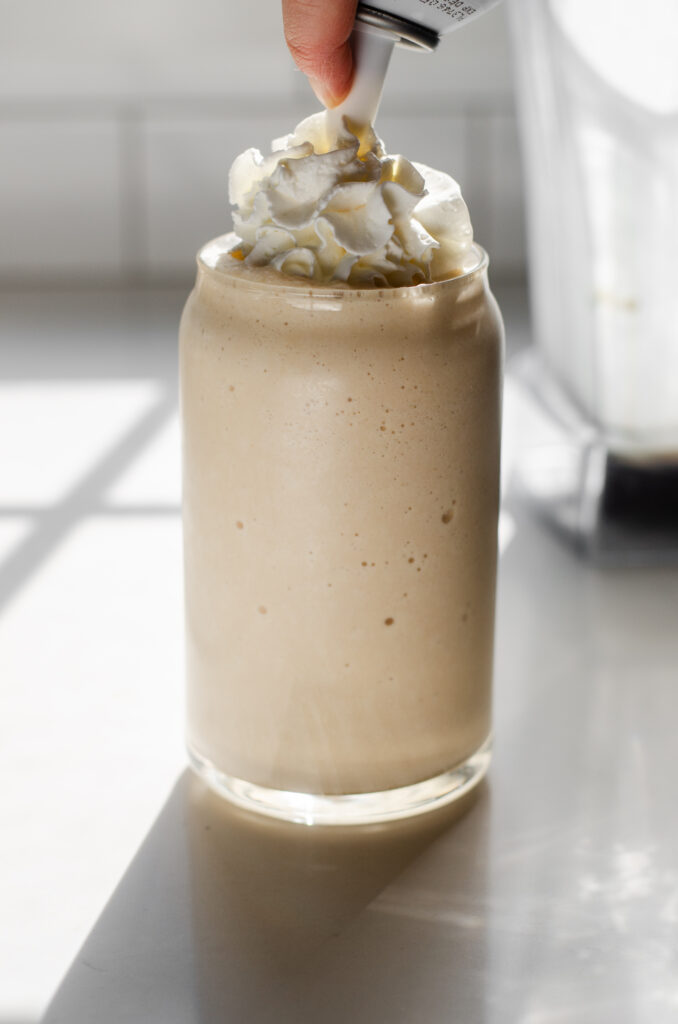 Topping the frozen drink with some whipped cream.