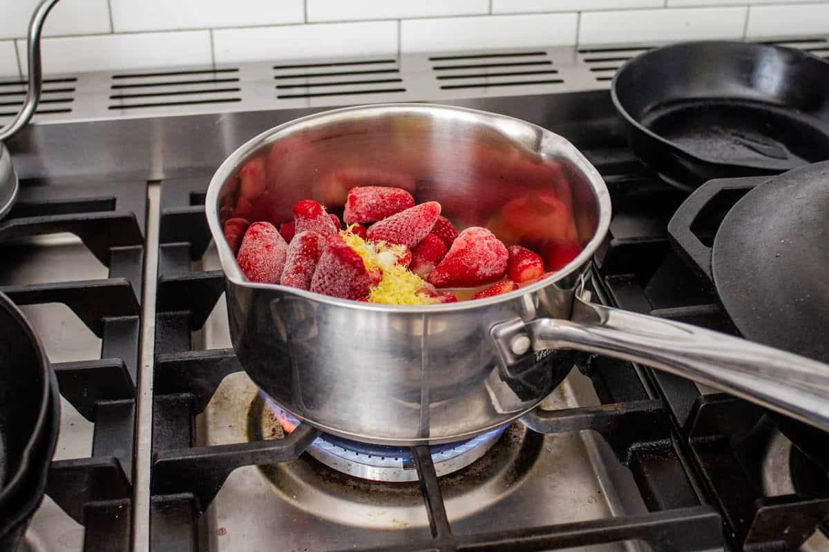 Placing the saucepan with all of the ingredients on the stove to cook.