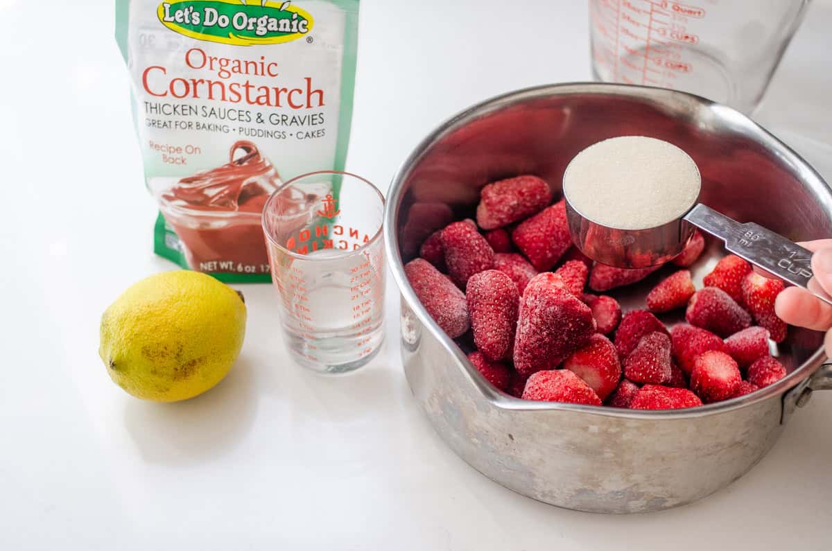 Adding the sugar to the strawberries in the pan.