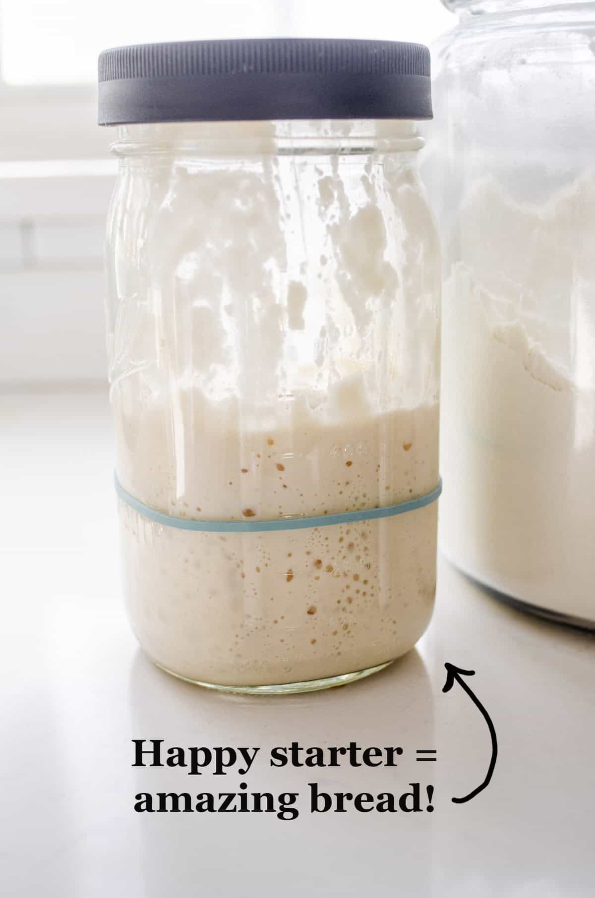 A jar of sourdough starter on a white countertop.